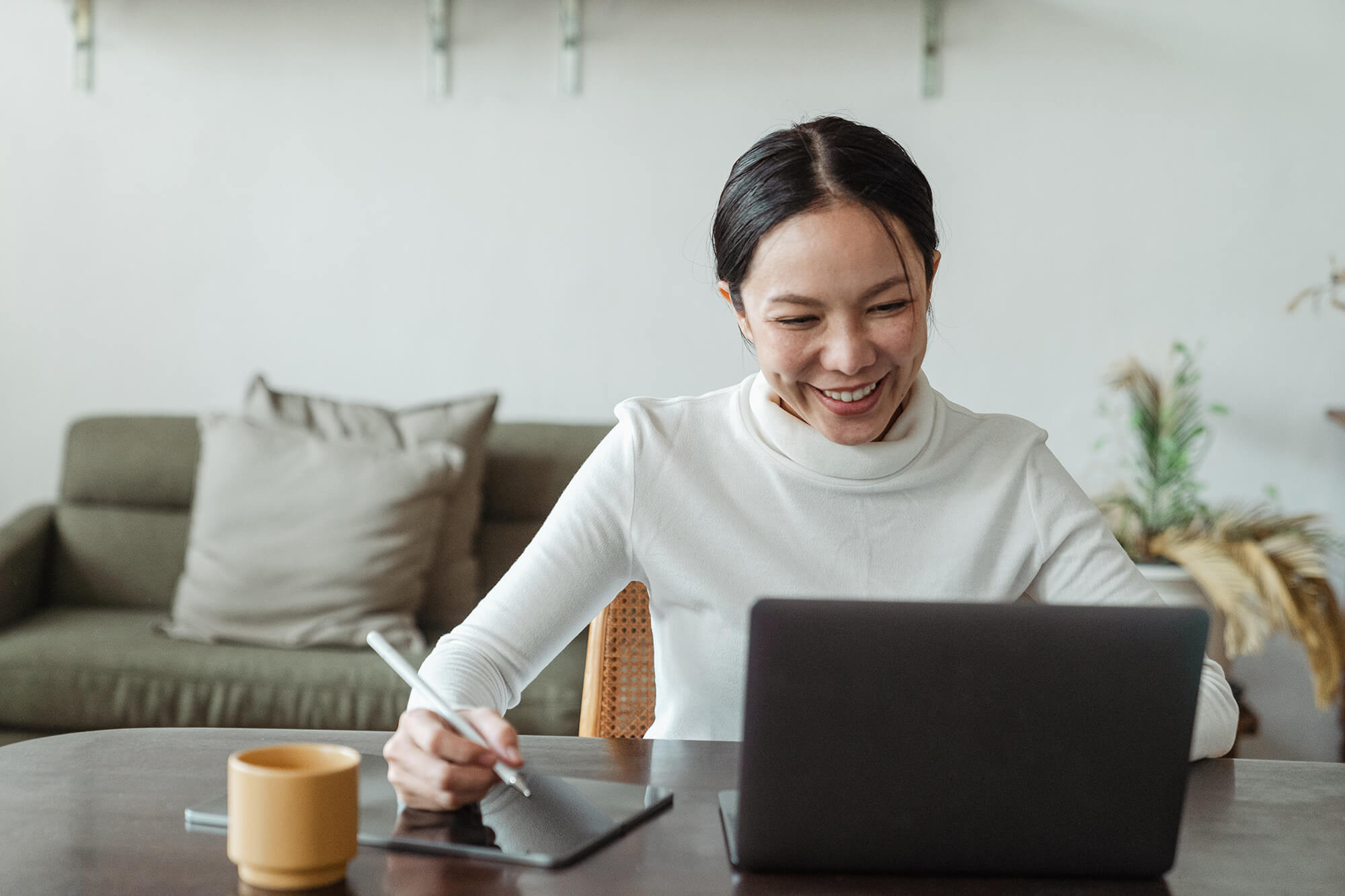 woman on a laptop with a coffee white turtleneck jumper 