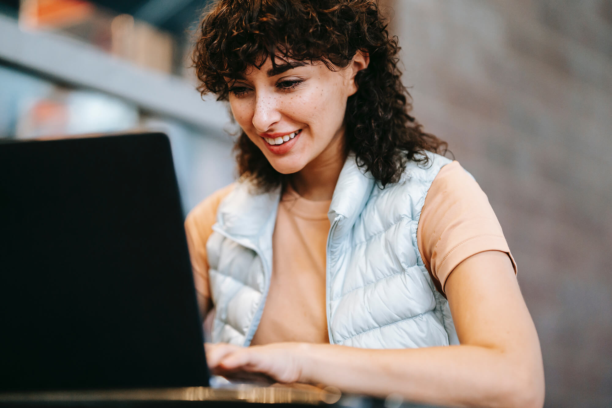 woman on laptop wearing puffer vest