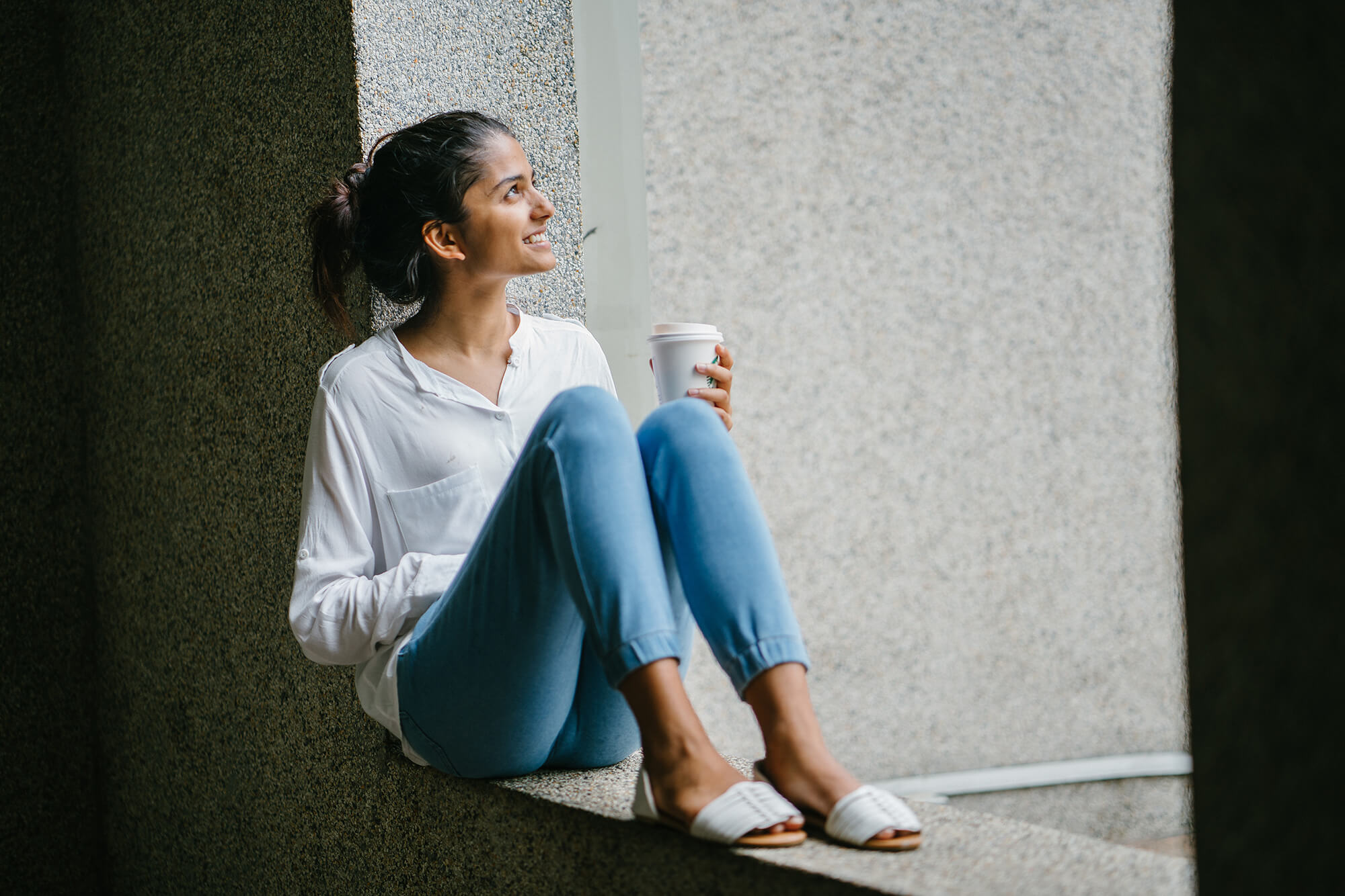 girl sitting drinking coffee looking away from shot 